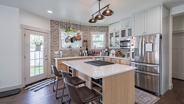 A modern kitchen with a large island, stainless steel appliances, and a brick accent wall. - Pet Friendly Downtown Vintage House w/ Hot Tub! (Idaho Falls)