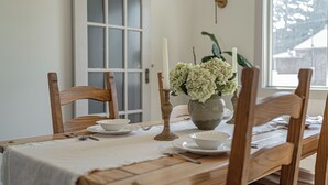 A dining table set with white plates, bowls, and a vase of flowers. - Pet Friendly Downtown Vintage House w/ Hot Tub! (Idaho Falls)