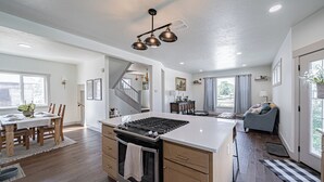 A spacious kitchen with a central island, wooden cabinets, and a modern light fixture. - Pet Friendly Downtown Vintage House w/ Hot Tub! (Idaho Falls)