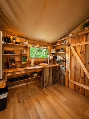 A rustic kitchen with wooden shelves, a window, and a sink.