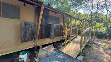 A rustic cabin with a wooden deck and a metal railing.