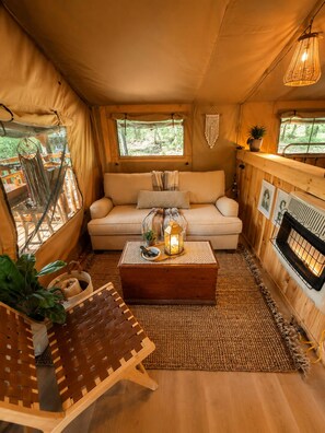 A cozy interior with a sofa, a wooden coffee table, a woven chair, and a fireplace.