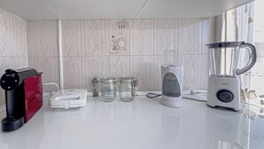 Una cocina con cafetera, licuadora y dos frascos de vidrio sobre la encimera.