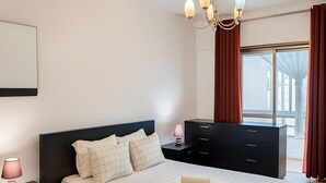 Un dormitorio moderno con una cama grande, una mesita de noche, un aparador y una araña.