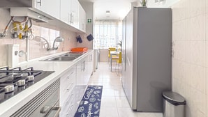 Una cocina moderna con gabinetes blancos, una estufa de acero inoxidable y un refrigerador gris.