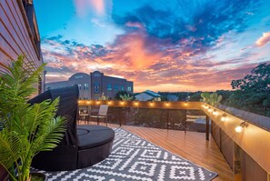 An outdoor deck with a round black sofa, a patterned rug, and string lights. - 2BR Designer Condo East Downtown Austin (Austin)