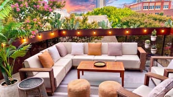 A modern outdoor seating area with a sofa, cushions, a table, and potted plants.