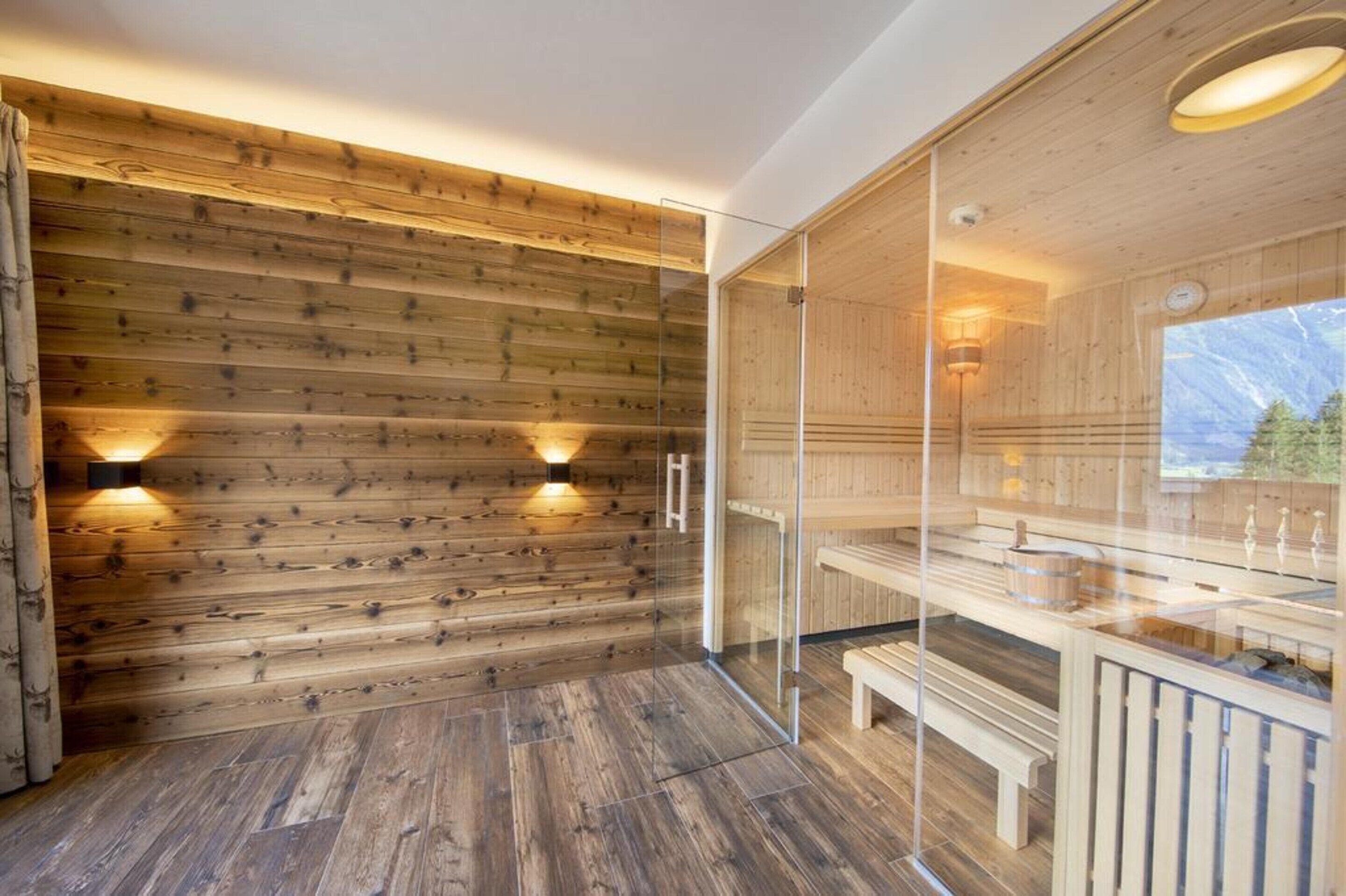 A wooden interior with glass walls, benches, and a sauna area.