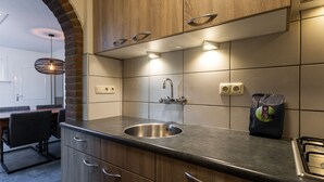 Une cuisine moderne avec des meubles en bois, un évier en acier inoxydable et une cuisinière à gaz.