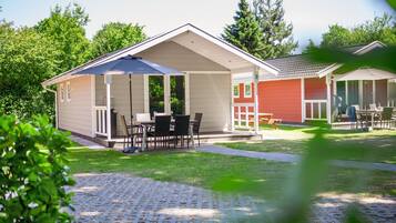 A small, single-story building with a covered patio area, a small outdoor seating area, and a paved walkway.