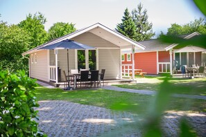 A small, single-story building with a covered patio area, a small outdoor seating area, and a paved walkway. - Apartment in Eindhoven Near City Center (Oirschot)
