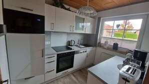 A modern kitchen with white cabinets, a built-in oven, a microwave, a sink, and a toaster. - Holiday Home Rubin Comfortable Vacation Home (Norden)