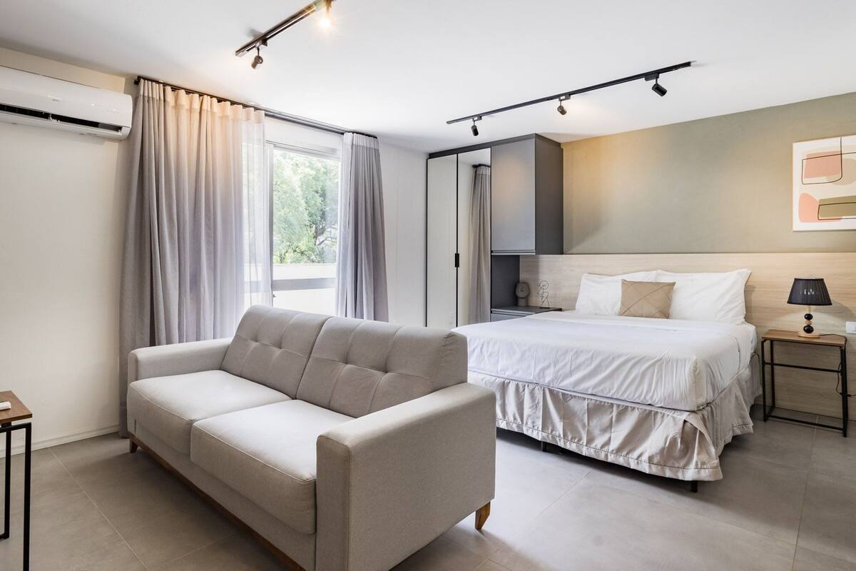 Um quarto moderno com uma cama, um sofá, uma mesa de cabeceira e ar condicionado fixado na parede.