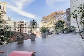 A rooftop terrace with potted plants, outdoor seating, and a view of surrounding buildings. - Duque by My Way (Porto Alegre)