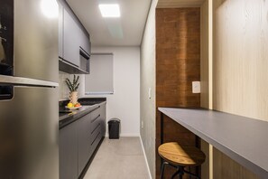 A compact kitchen with a refrigerator, a sink, and a wooden stool. - Duque by My Way (Porto Alegre)