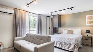 A modern bedroom with a sofa, a bed, a nightstand, and a wall-mounted air conditioner. - Duque by My Way (Porto Alegre)