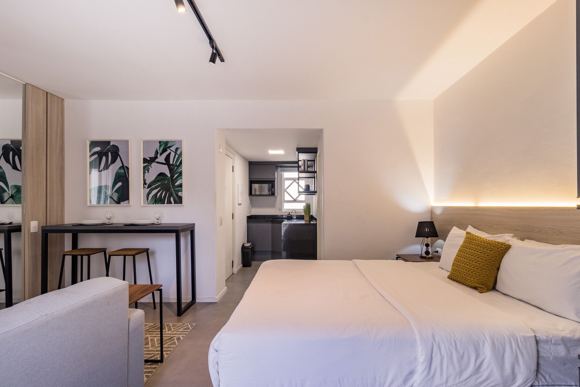 A hotel room with a bed, a desk, and a kitchenette.
