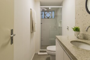 Une salle de bain avec douche, toilettes et lavabo.