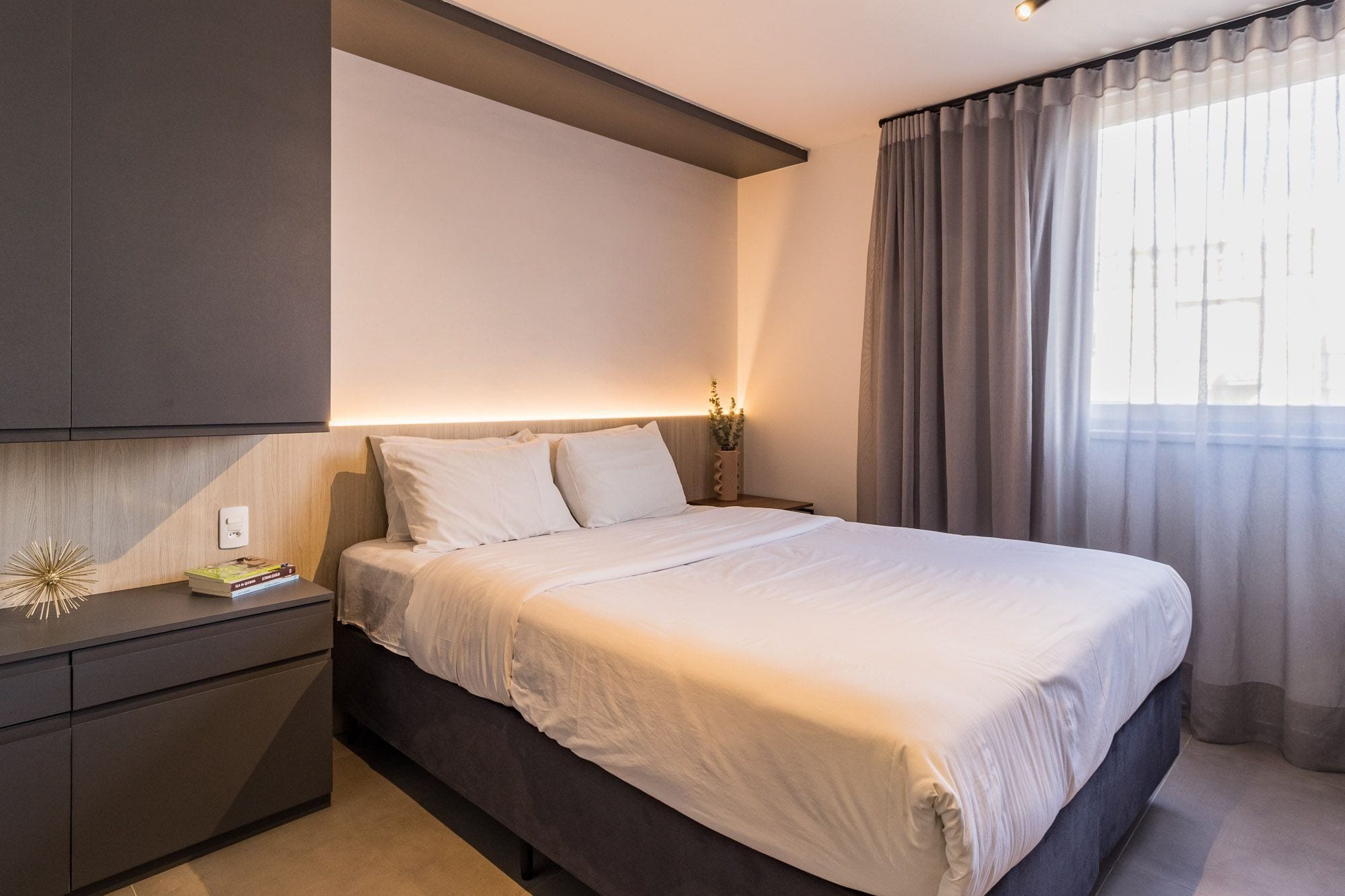 A modern bedroom with a bed, bedside table, and a nightstand.