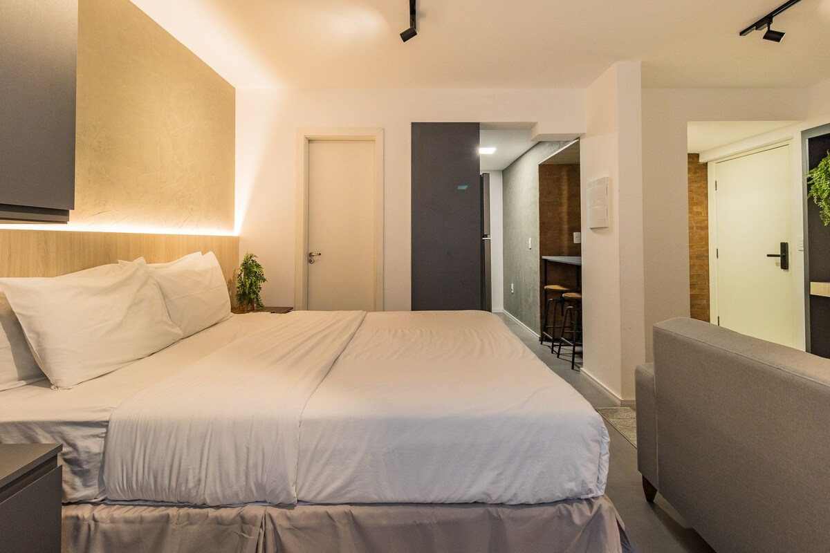 Une chambre d’hôtel moderne avec un grand lit, une table de chevet et un petit coin salon.