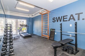 A gym with a treadmill, weight rack, bench, and a wall with 'SWEAT.' - Duque by My Way (Porto Alegre)