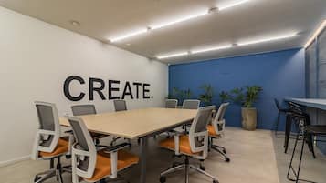 A conference room with a large table, six chairs, and a blue accent wall with the word 'CREATE.'