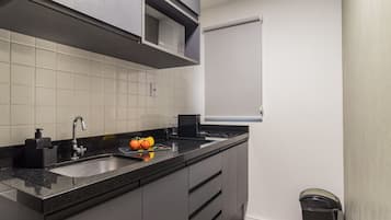 A modern kitchen with a black countertop, stainless steel sink, and a microwave above the stove.