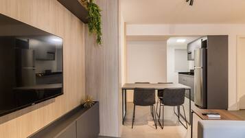 A modern kitchen with a built-in TV, a dining area with chairs, and a refrigerator.