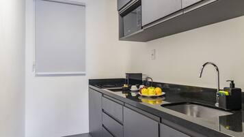 A compact kitchen with a built-in microwave, a sink, and a countertop with a fruit bowl.