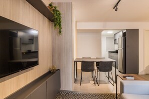 A modern kitchen with a built-in TV, a dining area with chairs, and a refrigerator. - Duque by My Way (Porto Alegre)