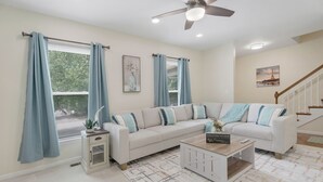 Una sala de estar con un sofá modular, una mesa de centro, una mesita auxiliar y una escalera.
