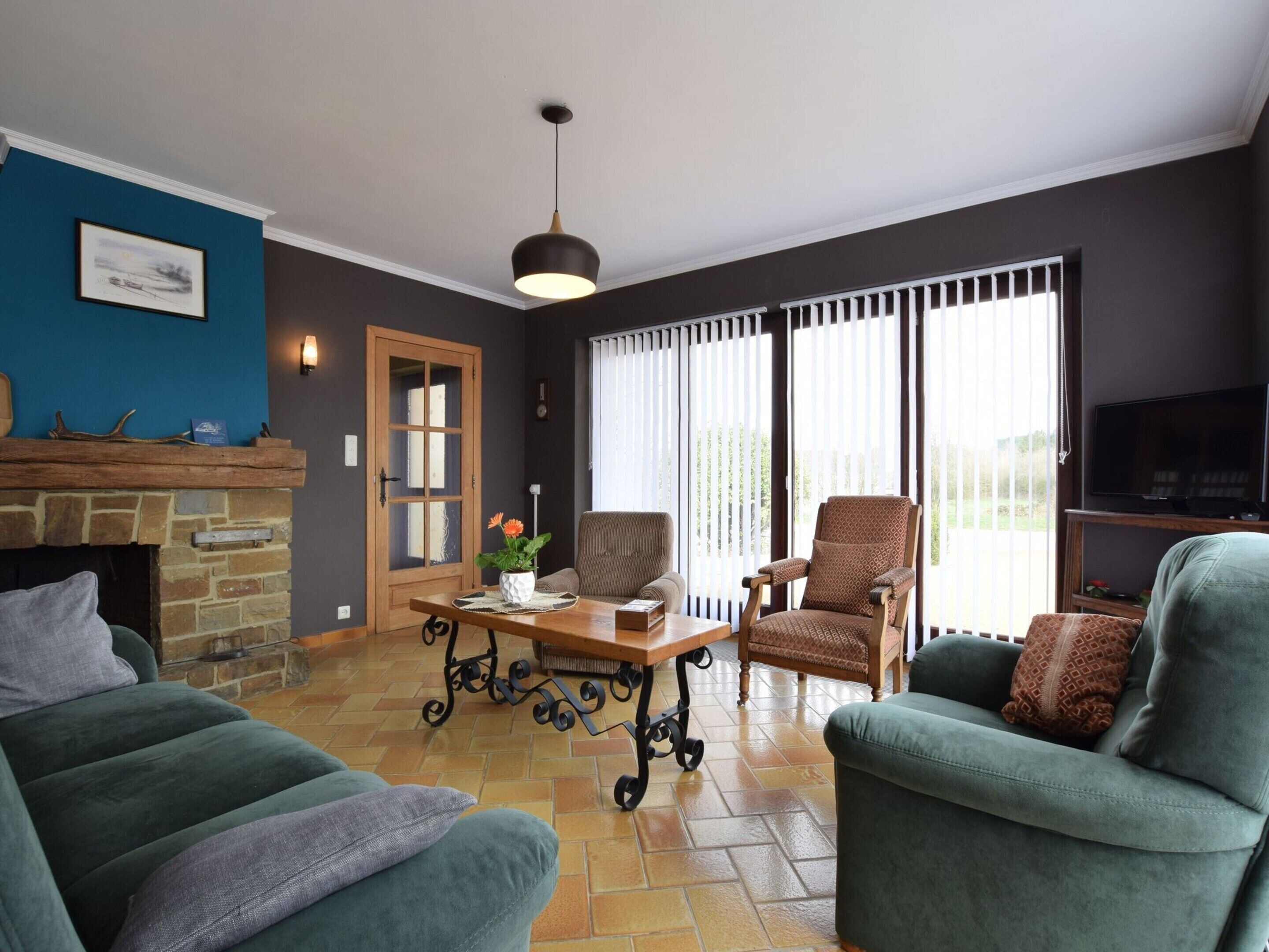 A living room with a fireplace, two armchairs, a coffee table, and a television.