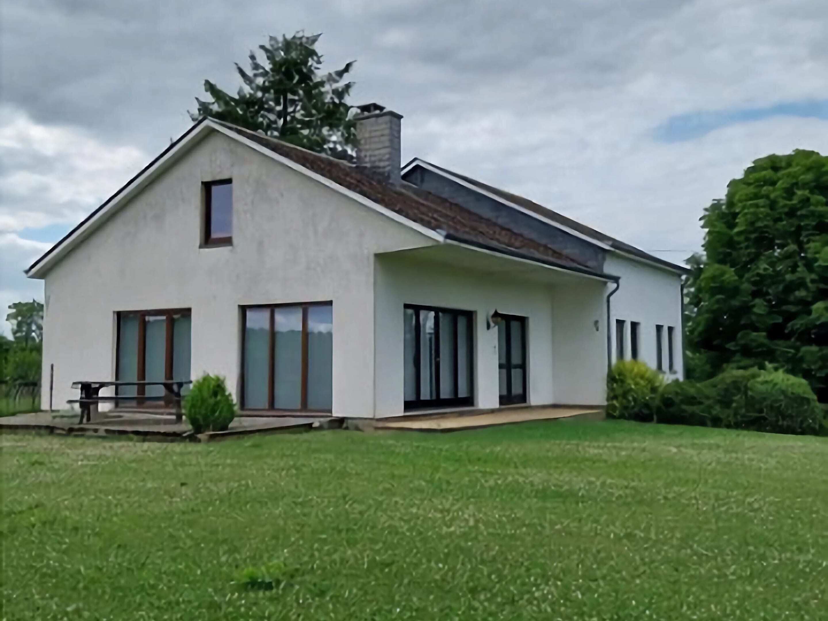 A modern single-story house with a large front lawn, a patio, and a chimney.