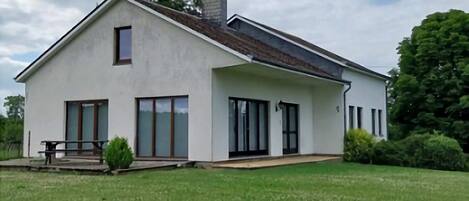 A modern single-story house with a large front lawn, a patio, and a chimney.