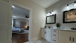 A bathroom with a marble floor, white cabinets, a large mirror, and a ceiling fan. - Richmond Ridge - 4BD/4.5BA and Garage (Richmond)