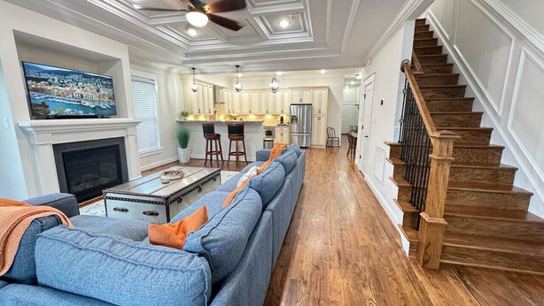 A spacious living room with a long blue sofa, a fireplace, and a kitchen in the background. - Richmond Ridge - 4BD/4.5BA and Garage (Richmond)