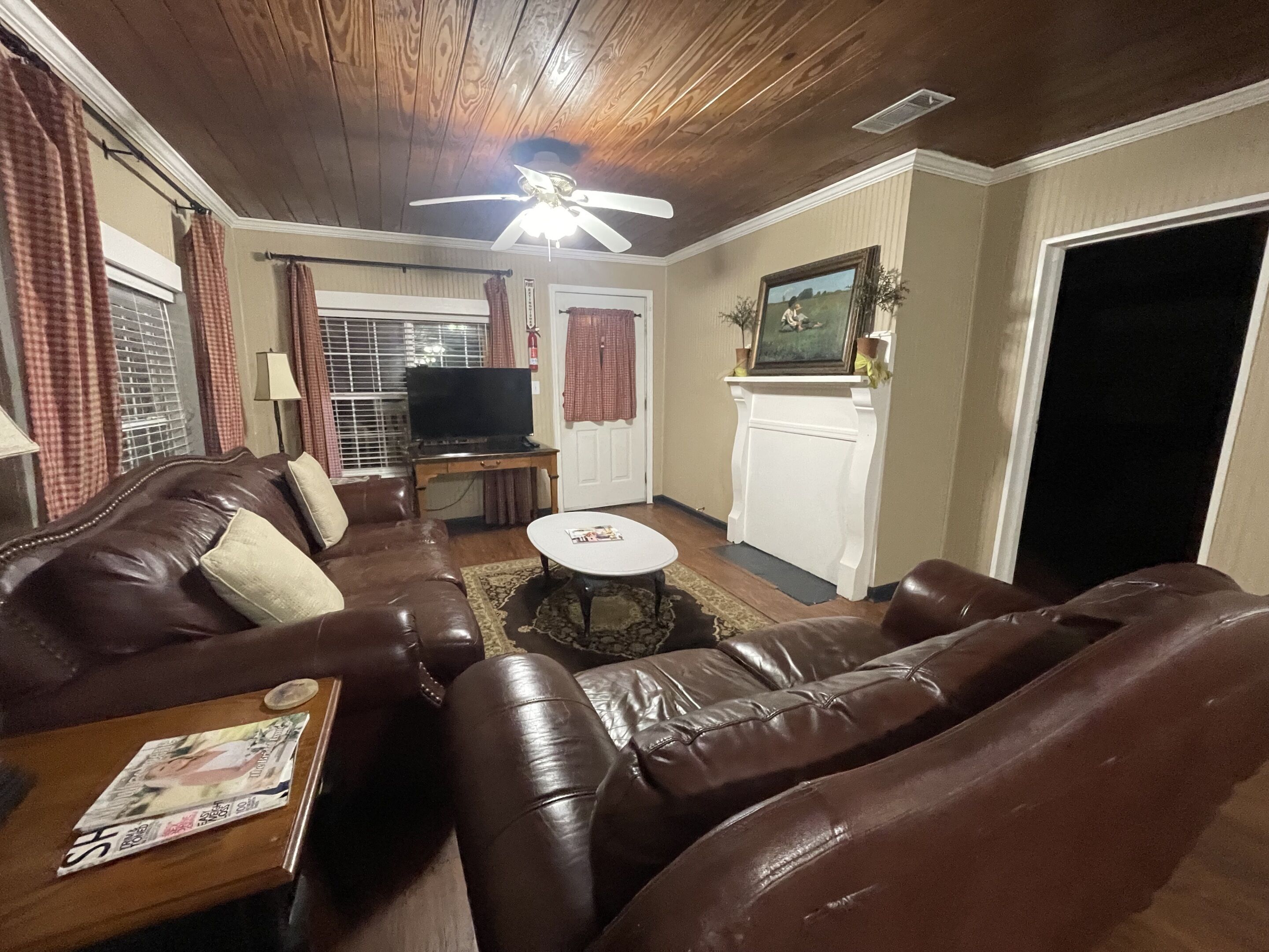 Una sala de estar con un sofá de cuero marrón, un televisor y una chimenea.