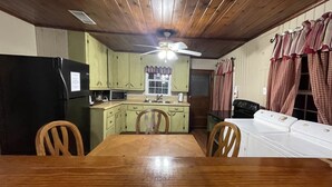 A kitchen with wooden cabinets, a dining table, chairs, a ceiling fan, and a washing machine.
