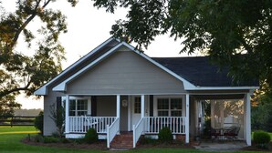 A single-story house with a front porch, a small front yard, and a covered outdoor seating area.