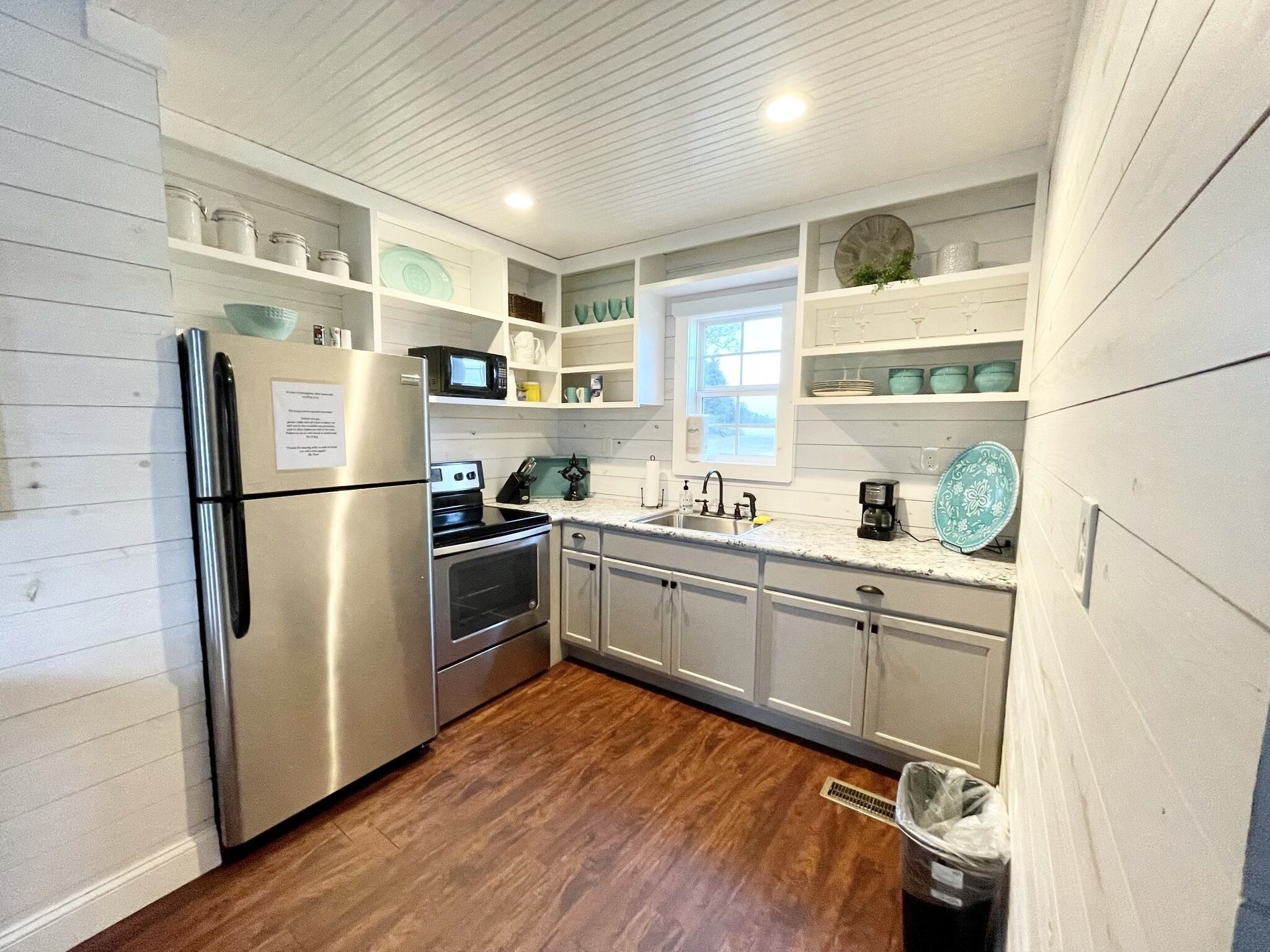 Una cocina con muebles blancos, electrodomésticos de acero inoxidable y un ventanal.