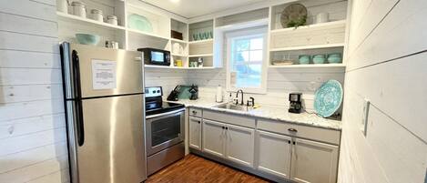 Una cocina con muebles blancos, electrodomésticos de acero inoxidable y un ventanal.