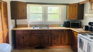 A kitchen with wooden cabinets, a double sink, a microwave, and a stove. - Cozy 1-bedroom apartment with WiFi, AC, full kitchen, in enjoyable Colebrook (Colebrook)