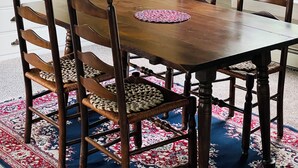 A dining area with a wooden table and chairs, a patterned rug, and a cabinet with bottles. - Cozy 1-bedroom apartment with WiFi, AC, full kitchen, in enjoyable Colebrook (Colebrook)