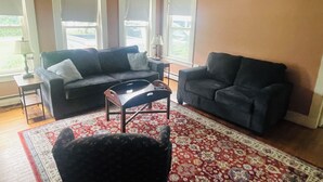 A living room with two dark sofas, a coffee table, and a patterned rug. - Cozy 1-bedroom apartment with WiFi, AC, full kitchen, in enjoyable Colebrook (Colebrook)