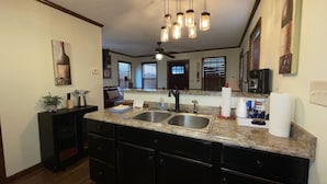 A kitchen with a granite countertop, stainless steel sink, and black cabinets.