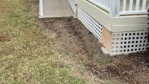 A house with a covered porch, a small deck, and a grassy yard.