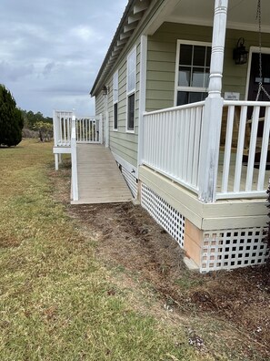 A house with a covered porch, a small deck, and a grassy yard.