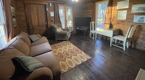 Una sala acogedora con un sofá, un televisor y una mesita.