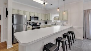 A modern kitchen with a large island, stainless steel appliances, and pendant lighting. - Elegant 3BR Condo: Magnolia North 101 (Myrtle Beach)