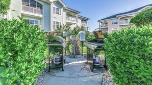 A pool area with two grill stations and a sign indicating grill hours. - Elegant 3BR Condo: Magnolia North 101 (Myrtle Beach)